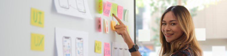 Girl pointing to a wall of post-it notes with various solutions, highlighting the process of brainstorming in the BCG interview process 2023.