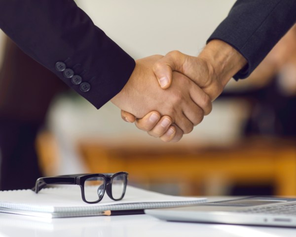 Two professionals shaking hands as a symbol of successful completion of a consulting case interview, reflecting the guidance offered by our consulting case interview cheat sheet